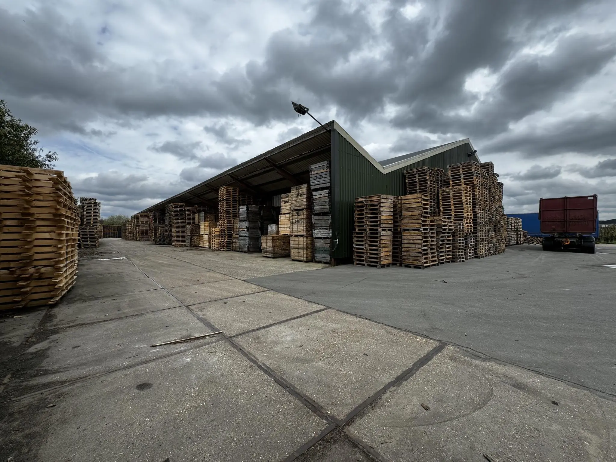 Opslagterrein met hoge stapels houten pallets en een vrachtwagen aan de Graaf van Lynden van Sandenburgweg.